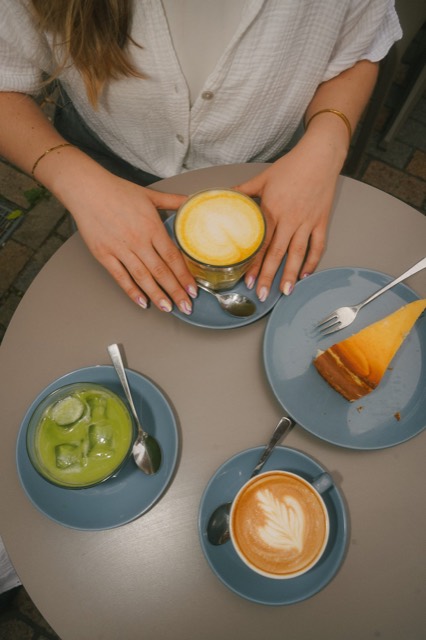 Gepflegte Hände mit Latte Macchiato und Matcha im Café