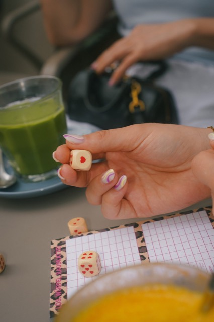 Hand mit Nagel-Design hält einen Würfel